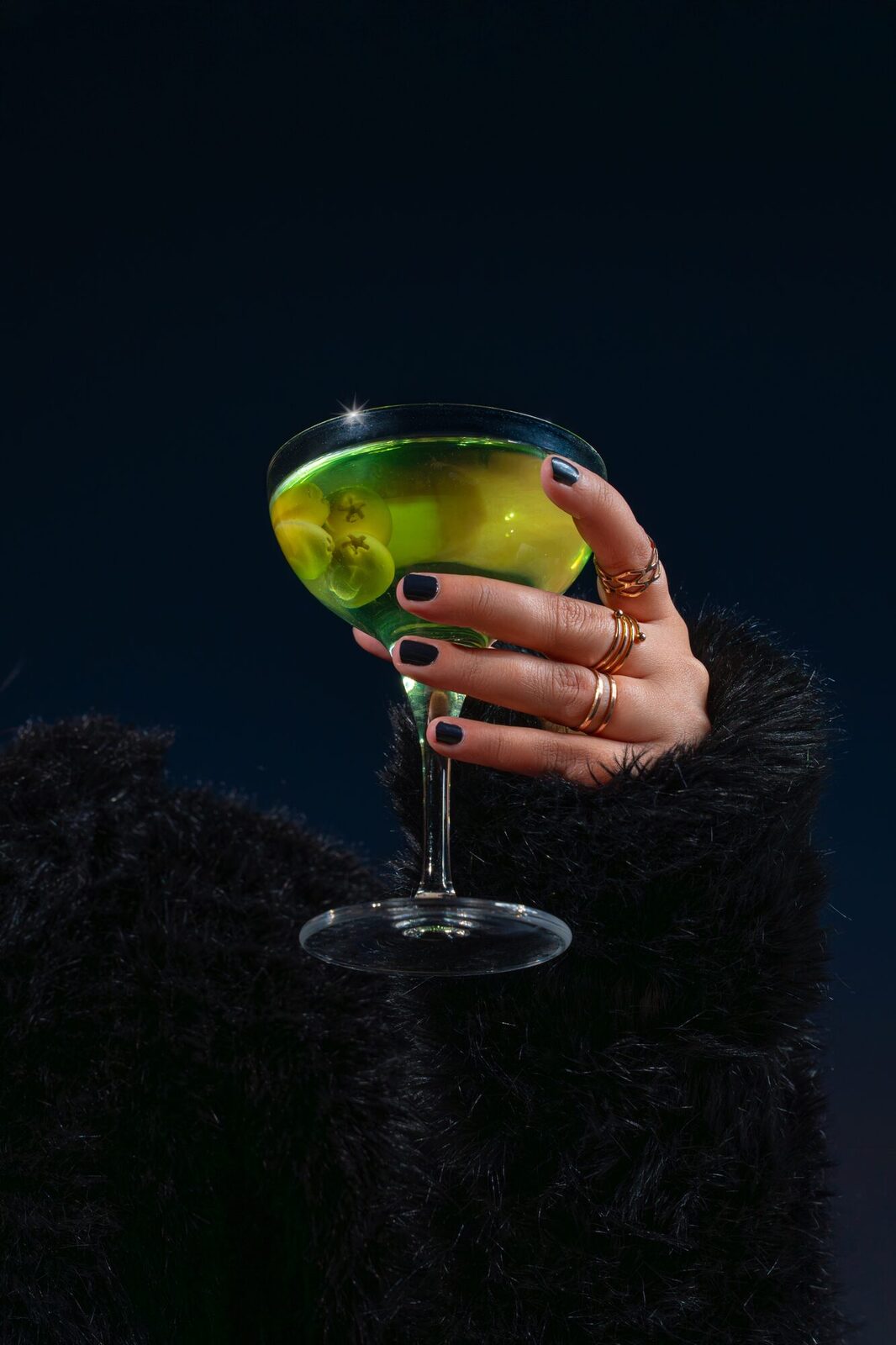 Emerald-green cocktail with ice, bar setting